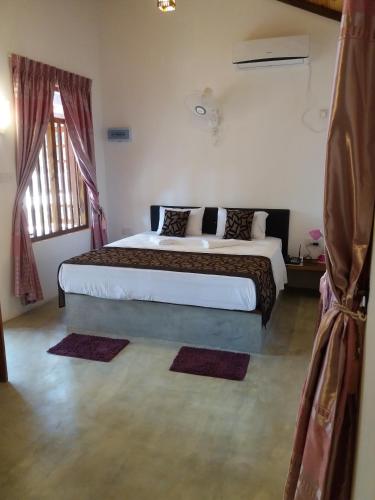 a bedroom with a large bed and a window at So-J Beach Villa in Trincomalee