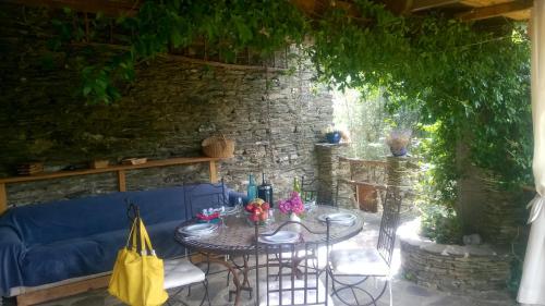 a patio with a table and a blue couch at Les Gîtes De La Bastidette in Saint-Martin-de-Boubaux