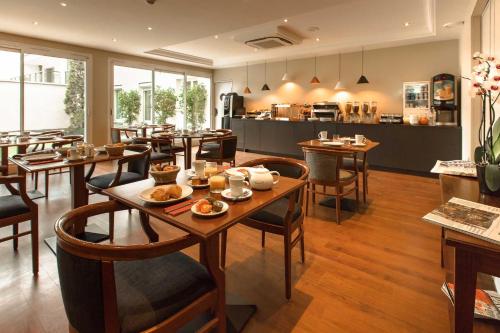 un restaurant avec des tables et des chaises en bois et une cuisine dans l'établissement Hotel Montbriand Antony - Ancien Alixia, à Antony