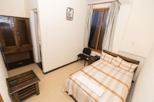 a bedroom with a bed and a chair and a window at Honey Land Hotel Lalibela in Lalībela