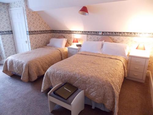 a hotel room with two beds and two lamps at The Darnley Hotel in Ilfracombe