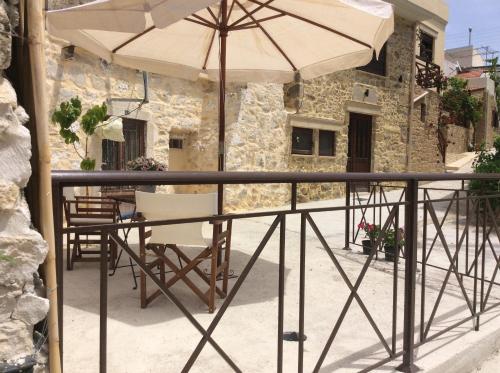 a table with an umbrella and chairs on a balcony at kritikies1 in Pitsidia