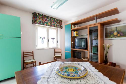Appartamento Telese Terme في تيليسي: غرفة طعام مع طاولة خشبية عليها لوحة