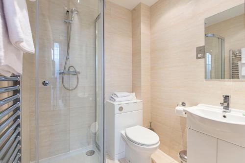 a bathroom with a shower and a toilet and a sink at The Maltings Tower Bridge Apartment in London