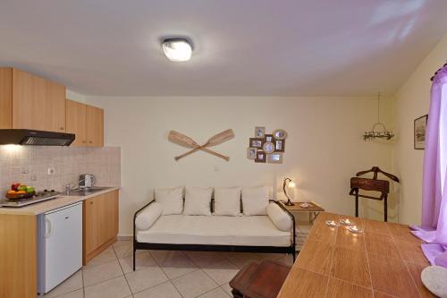 a living room with a white couch and a kitchen at Antouanetta Apartments in Ermoupoli