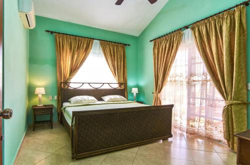 a bedroom with a bed with green walls and windows at Hispaniola Residencial in Sosúa