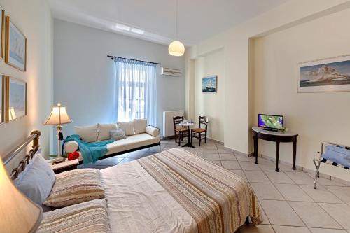 a hotel room with a bed and a couch at Antouanetta Apartments in Ermoupoli