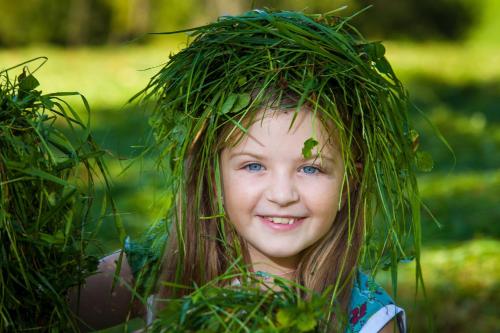 a little girl with areath of grass on her head at Ferienwohnung Bognerhof in Sankt Veit im Pongau