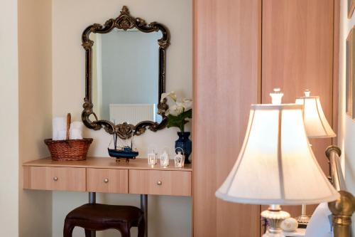a mirror on a wall next to a table with a lamp at Antouanetta Apartments in Ermoupoli