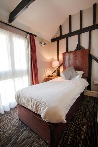 a bedroom with a large bed with a wooden headboard at The Saracens Head Hotel - The Coaching Inn Group in Great Dunmow