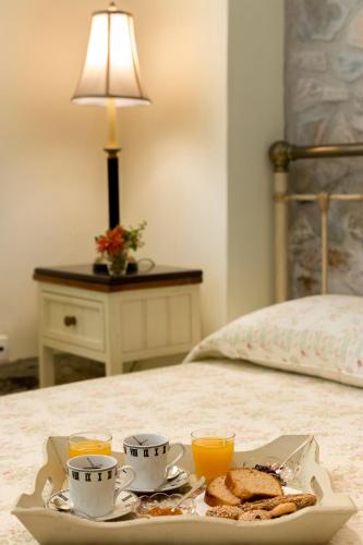 a tray of breakfast food on a bed with orange juice at Antouanetta Apartments in Ermoupoli