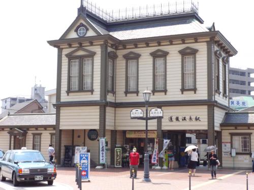 a building on the corner of a street with people in front at Nest Hotel Matsuyama in Matsuyama
