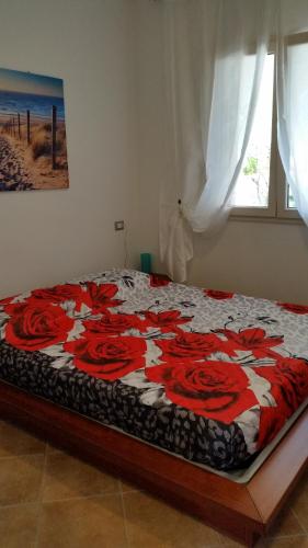 a bed with red roses on it in a bedroom at Appartamento l'Aurora in Santa Teresa Gallura