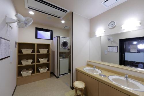 a bathroom with two sinks and a television in it at Hotel Route-Inn Sendaiizumi Inter in Sendai