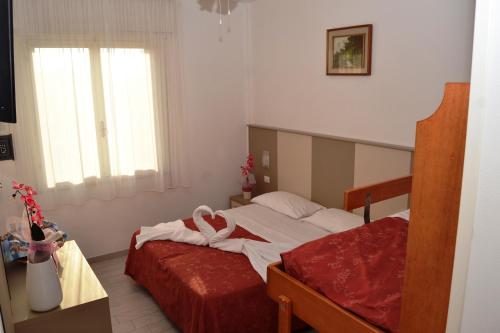 a bedroom with a bed with red sheets and a window at Hotel Zenith in Cervia