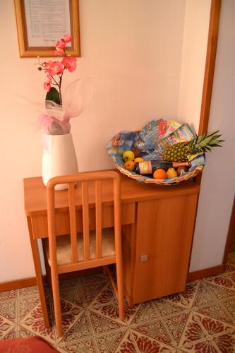 a table with a bowl of fruit and a vase of flowers at Hotel Zenith in Cervia