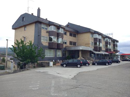 a large building with cars parked in a parking lot at Hostal los Rosales in Almázcara