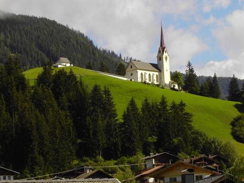 a church on top of a green hill with houses at Brunnerhof in Strassen