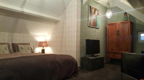 a bedroom with a bed and a tv in it at Boutique Hotel Villa de Proosdij in Klimmen