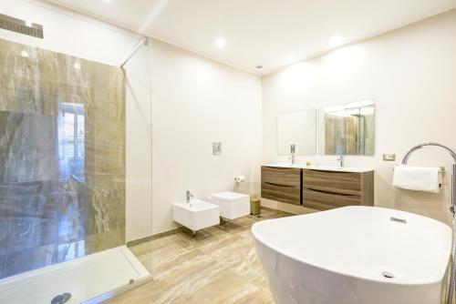 un bagno bianco con vasca e lavandino di RHS Rienzo Suites a Roma