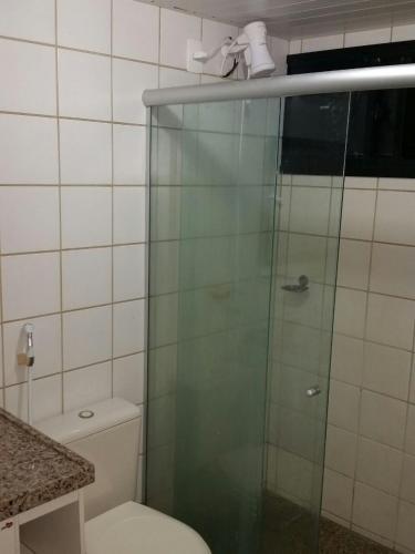 a bathroom with a toilet and a glass shower at Resort Aquaville Apartmento in Aquiraz