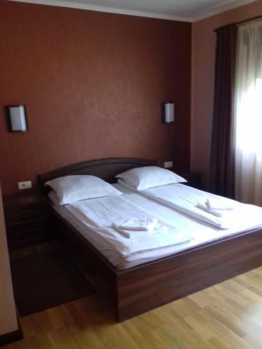 a bed with white sheets and pillows in a bedroom at Pensiunea Damiris in Baile Felix