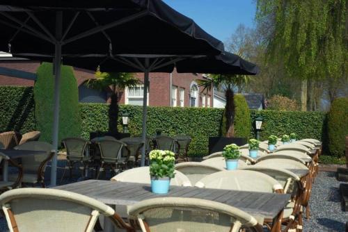 a row of tables with chairs and an umbrella at Hotel Restaurant de Sleutel in Riethoven