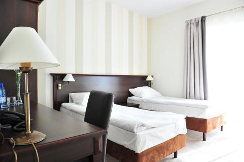 a hotel room with two beds and a desk with a lamp at Hotel Biały Dwór in Okuninka