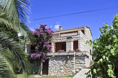 a stone house with a tree with purple flowers at Apartman Damir in Sumartin