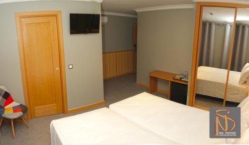 a hotel room with two beds and a television at Rocha Prestige - Guest House and Suites in Portimão