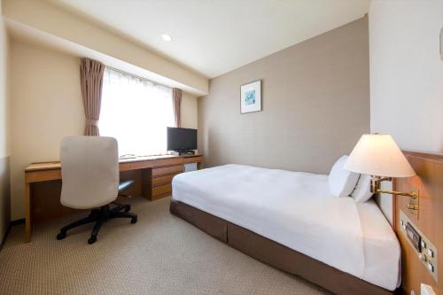 a hotel room with a bed and a desk and a computer at Rembrandt Hotel Tokyo-Machida in Machida