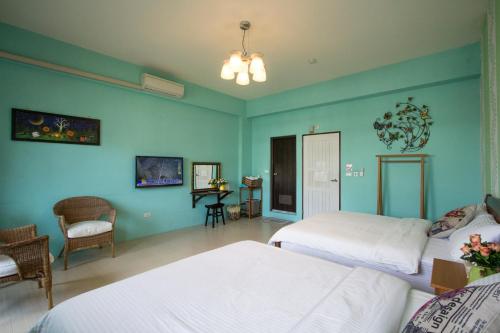 a bedroom with two beds and a table and chairs at Vicking Guesthouse in Taitung City
