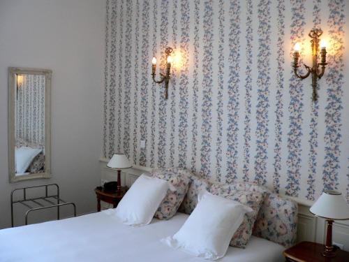 a bedroom with a white bed with a floral wallpaper at Chateau de la Rozelle in Cellettes