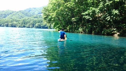 a man riding a paddle board on a river at Nori's Sharehouse Hakuba in Hakuba