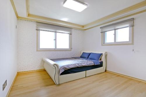 a small bed in a room with two windows at Geoje Blueberry Pension in Geoje 
