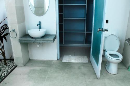 een badkamer met een wastafel, een toilet en een spiegel bij Villa Putih Lovina in Lovina