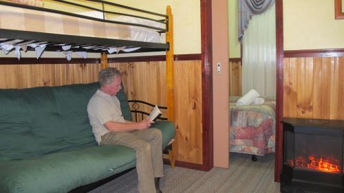 un uomo seduto su un divano in una stanza con un letto a castello di Cedar Lodge Cabins a Mount Victoria