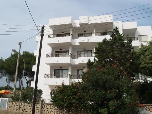 a white building with a tree in front of it at Apartamentos Mar Bella in Es Cana