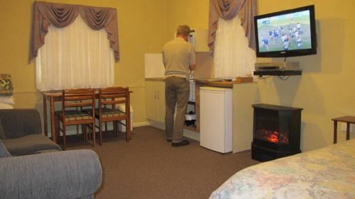 Un uomo che gioca a un videogioco in una stanza d'albergo di Cedar Lodge Cabins a Mount Victoria
