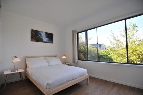 a bedroom with a bed and a large window at Leski Club in Jindabyne