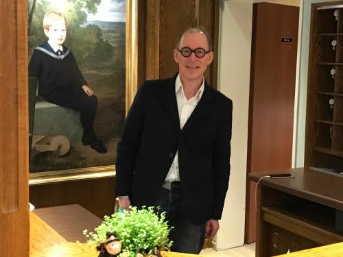 a man wearing glasses standing in front of a painting at Das Hotel Ostseeblick in Lütjenburg