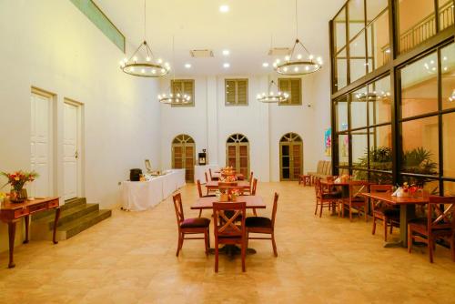 a dining room with tables and chairs and windows at The Source At Sula in Nashik
