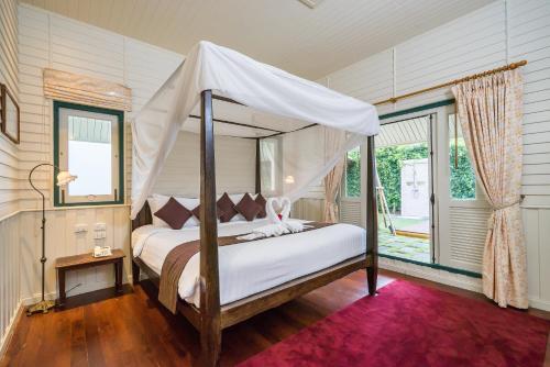 a bedroom with a bed with a canopy at KALANAN Riverside Resort former Buddy Oriental Riverside in Nonthaburi