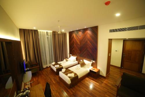 a living room with two couches and a television at Woodies Bleisure Hotel in Kozhikode