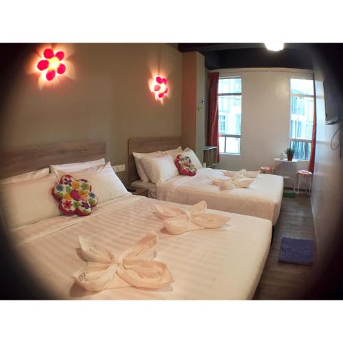 two beds in a room with flowers on them at Hotel Flora Plus in Cameron Highlands