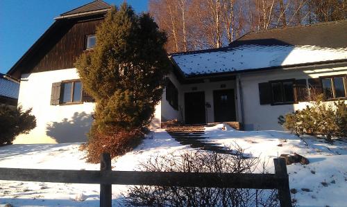 a white house with a fence in the snow at Ferienhaus Ahornweg in Bad Kleinkirchheim