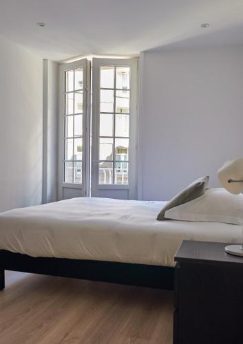 une chambre avec un grand lit et deux fenêtres dans l'établissement L'Annexe, à Saint-Malo