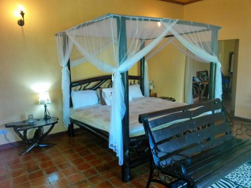 a bedroom with a canopy bed and a bench at Mwanzo Lodge in Naivasha