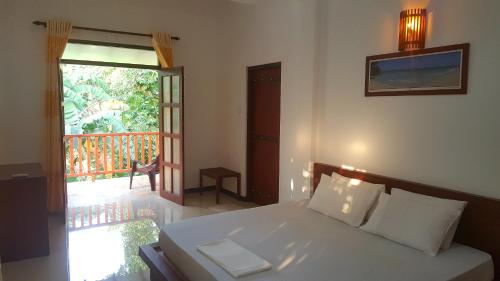 1 dormitorio con 1 cama y puerta a un balcón en Villa Happy Home, en Bentota