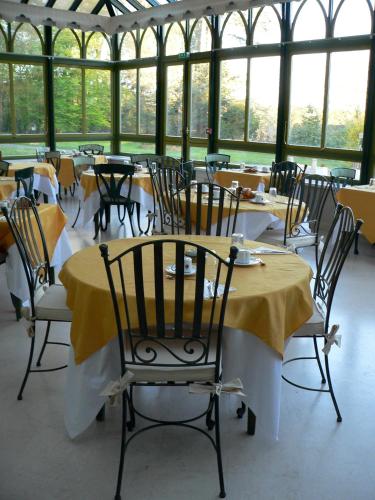 a dining room with tables and chairs and windows at Chateau de la Rozelle in Cellettes